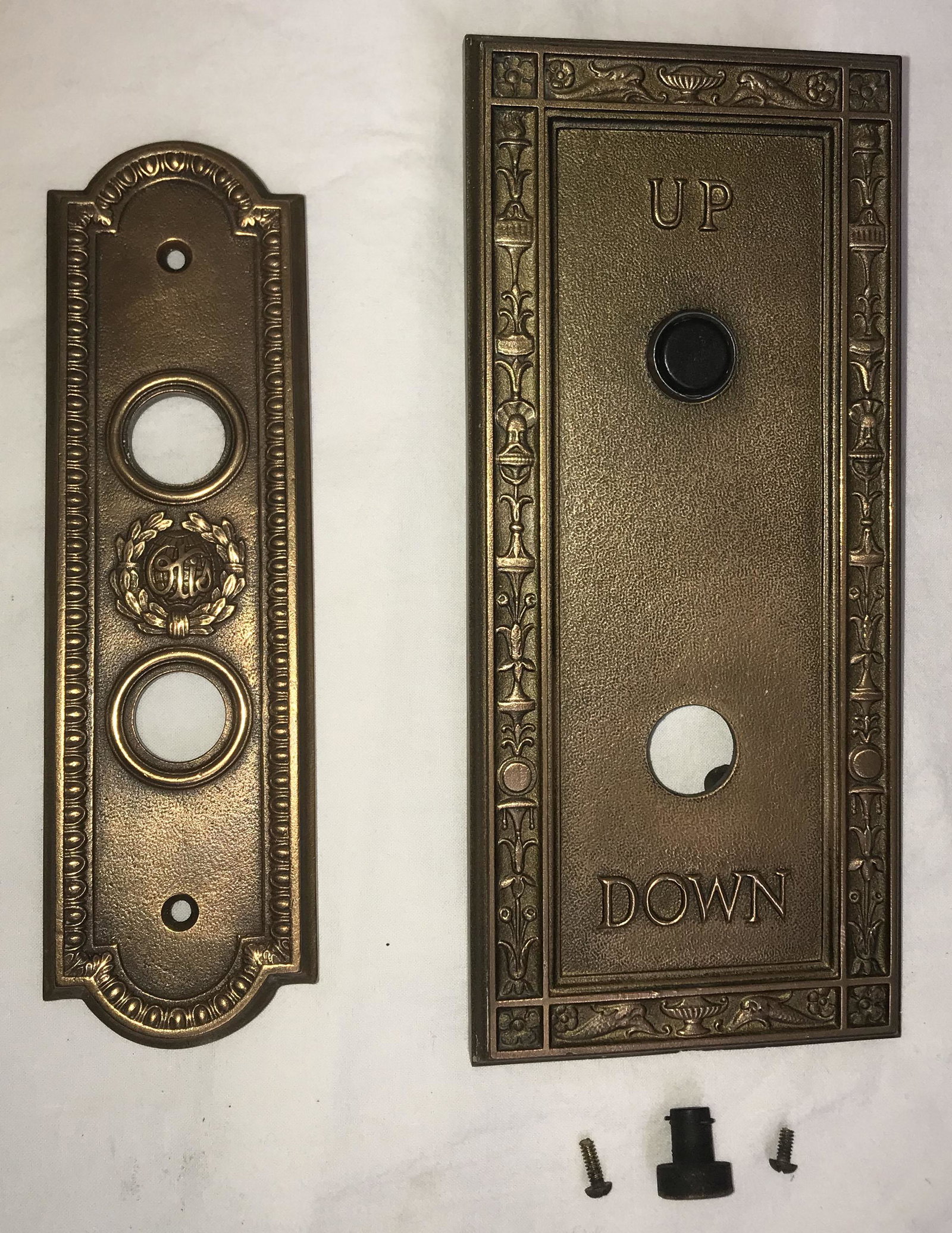 Vintage UP/DOWN Elevator Switch: (2) vintage bronze elevator UP/DOWN switch plates: (1) marked Otis, marked on back 1672SW4, no buttons, 8 1/8" x 2 3/8" W; AND (1) decorated w/rosettes, shell, flame, floral and dolphin design w/both 