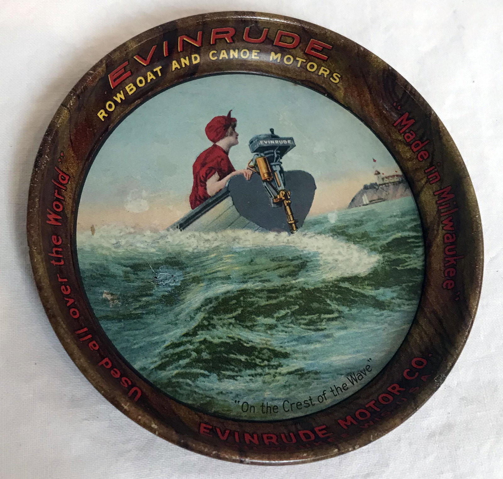 Vintage Tin Tip Tray: Vintage round tin tip tray advertising Evinrude Rowboat and Canoe Motors, Evinrude Motor Co., Milwaukee, WIS., USA, "Used all over the World", scene of a lady dressed in red piloting a boat entitled "