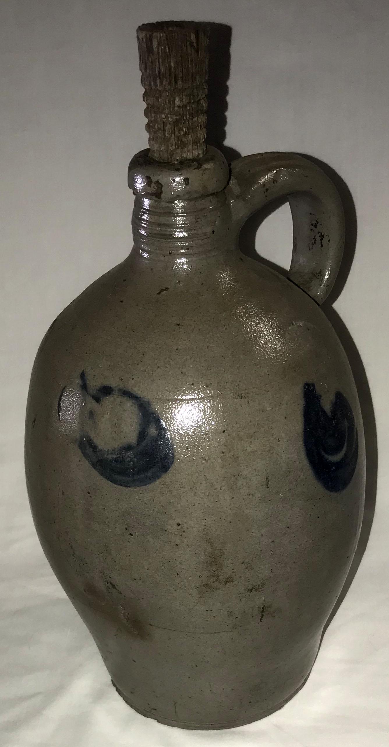 Blue Decorated Stoneware Jug: 19th century blue decoration gray stoneware jug w/handle, leaf and circular design; some roughness and chipping visible at base, various hairline cracks, chip visible on handle, 12" T x 6 3/4" diamete