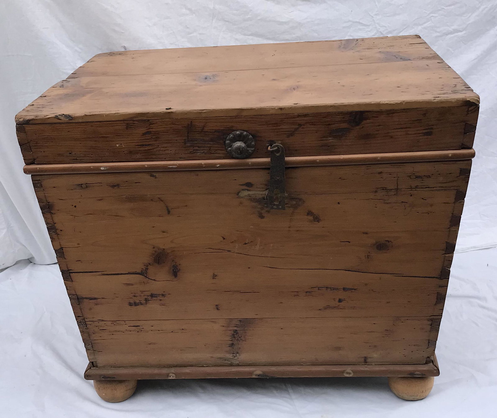 Primitive Dovetailed Chest: Primitive country pine dovetailed chest on bun feet, feet may have been added, old refinish, iron latch, knob and side ring handles, rectangular shape tapering to base, old wear, scratches, worm holes