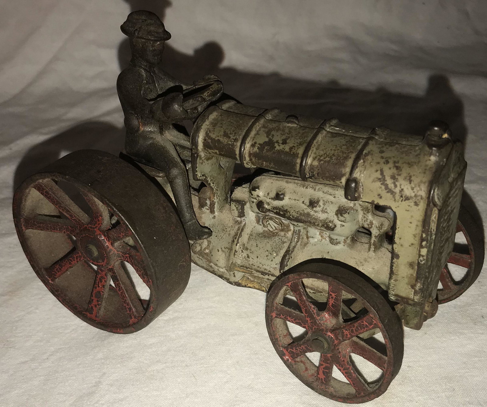 Vintage Cast Iron Farm Tractor: Vintage cast iron Fordson toy farm tractor, old original gray and red painted surface showing worn paint and rust, surface on driver appears slightly more crisp and clean than the tractor, 4" T x 5 5/