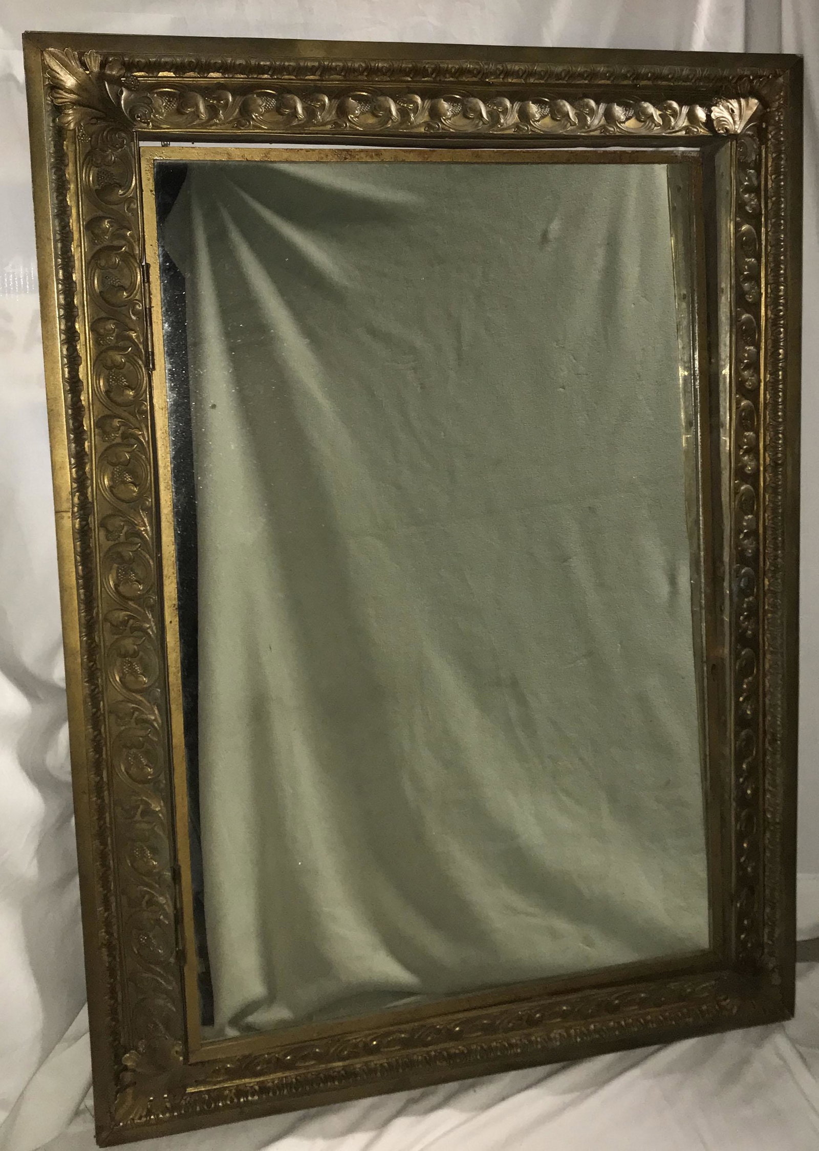 Ornate Hinged Mirror: Large ornate brass over wood frame, ornate scrolled leaf and berry design w/leaf corners having a hinged mirrored door possibly used in front of a wall safe; 1 hinge needs to be refastened, glass prob