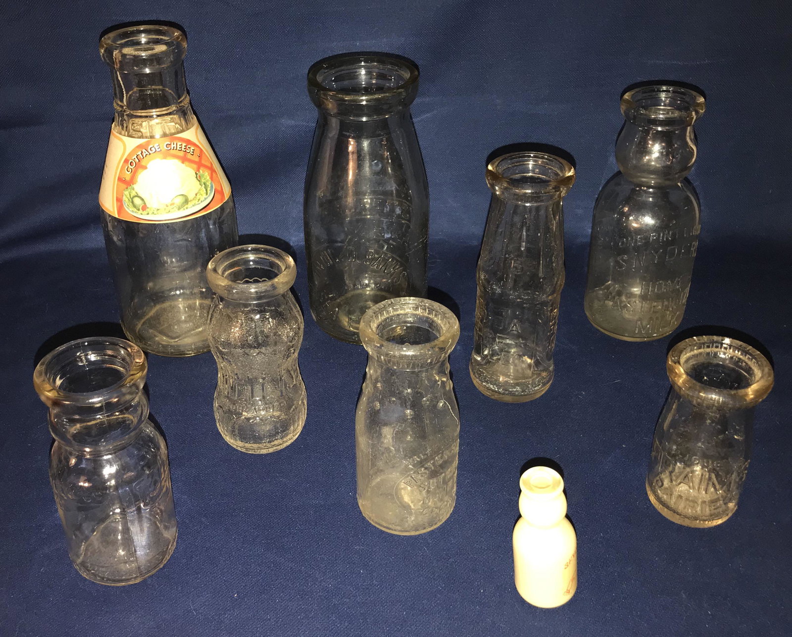 Grouping of Milk Bottles: Grouping of vintage dairy and store bottles: Alderney Dairy, Newark, NJ 1 quart bottle w/paper cottage cheese label, 9 1/4" T'; Snyder's Home Pasturized milk bottle w/cream top, 1 pint, 7 1/4" T; Blue