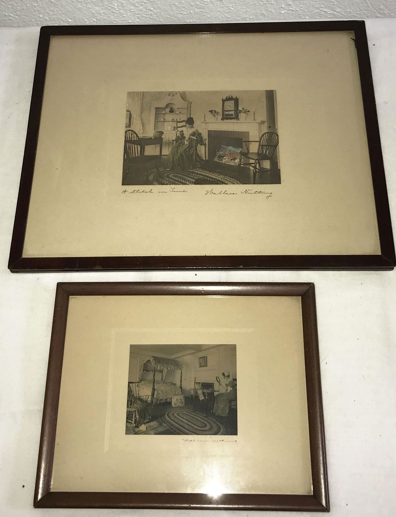 Wallace Nutting Handcolored Photographs: (2) framed Wallace Nutting handcolored photographs: interior scene of young lady seated by a table looking into what appears to be a mirror, room decorated w/canopy bed, oval braided rug, hat box, fir