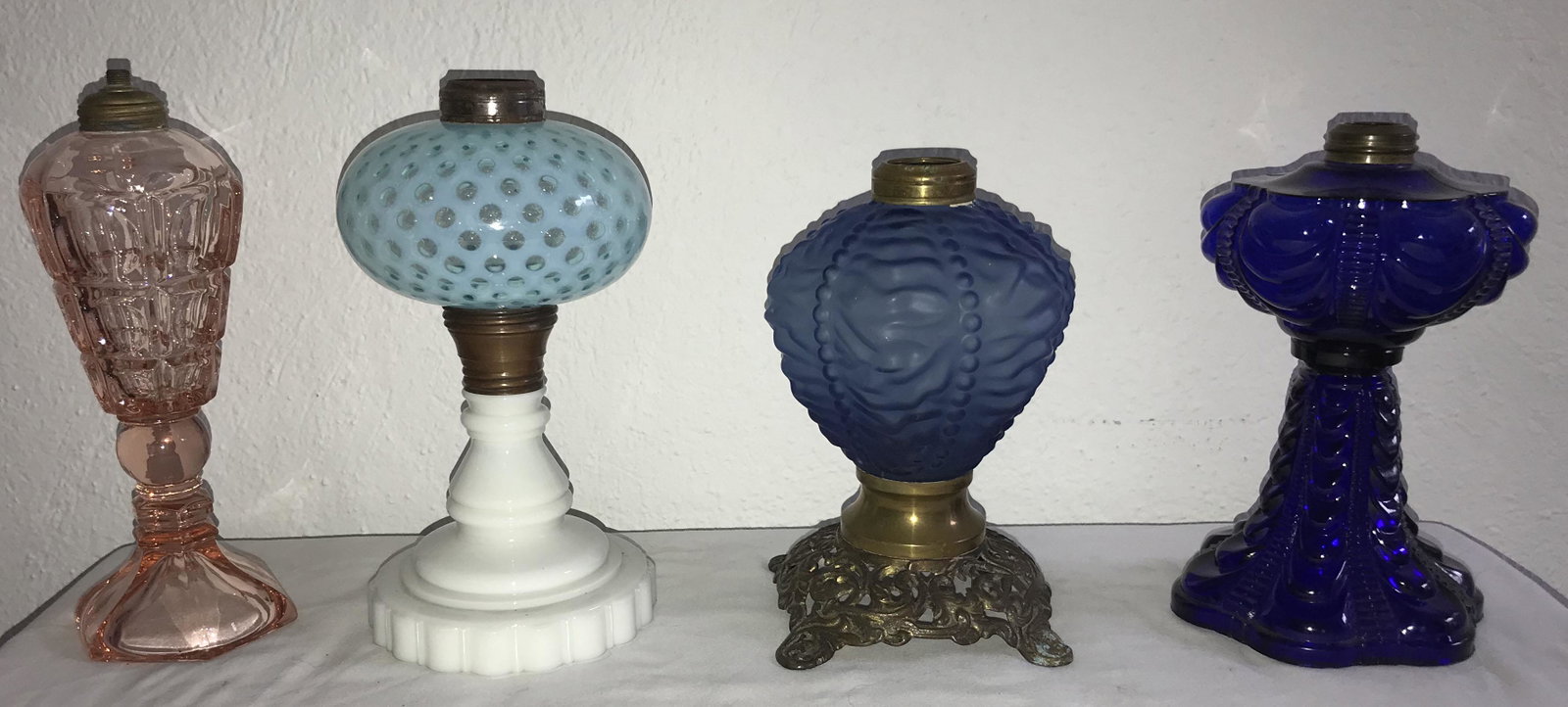 Grouping of 4 Vintage Oil Lamp Bases: Grouping of 4 vintage oil lamp bases: pink glass whale oil lamp, thumbprint design w/hexagonal base, 10" T; lamp w/opalescent blue "bubble" design font on a round milkglass base, 9 3/4" T; blue satin 