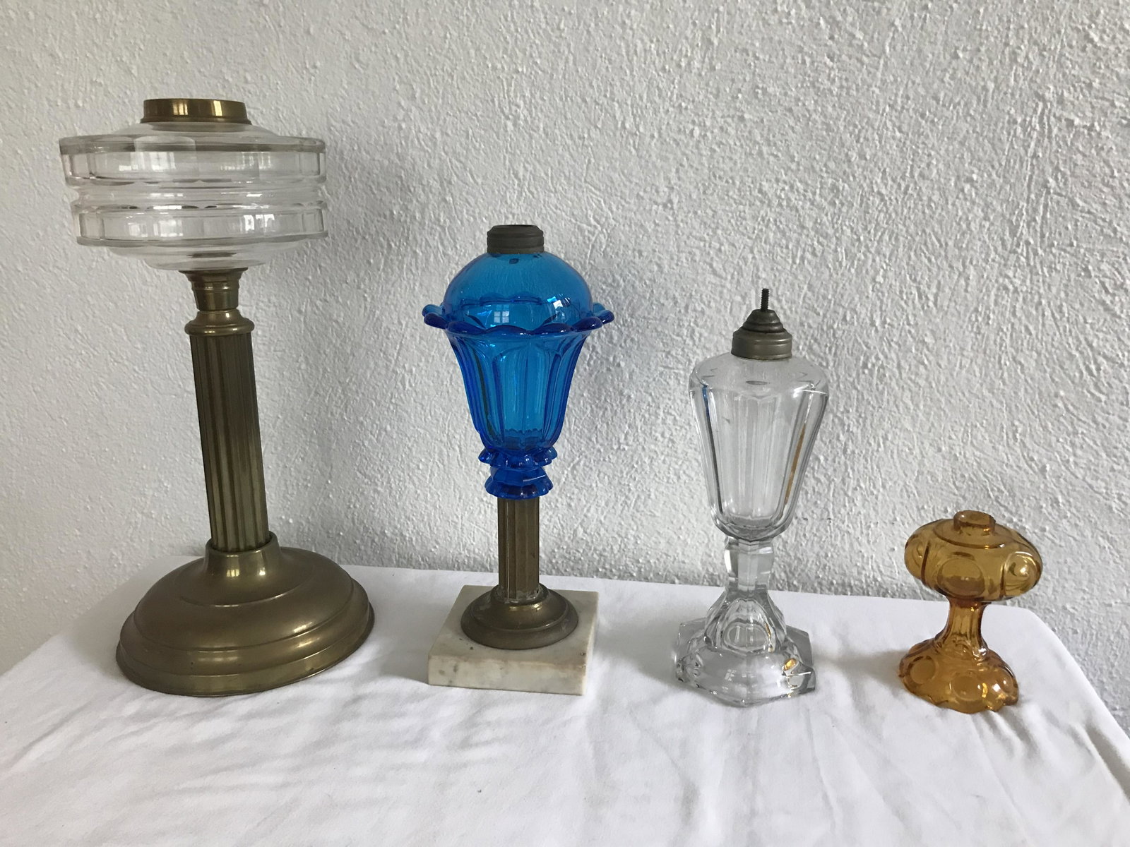 Grouping of 4 Vintage Oil Lamp Bases: Grouping of 4 vintage oil lamp bases: lamp w/clear glass panel cut font and brass column, round weighted base, 14 1/4" T x 6 7/8" base diameter; blue glass inverted pear shape font, pie crust and pane