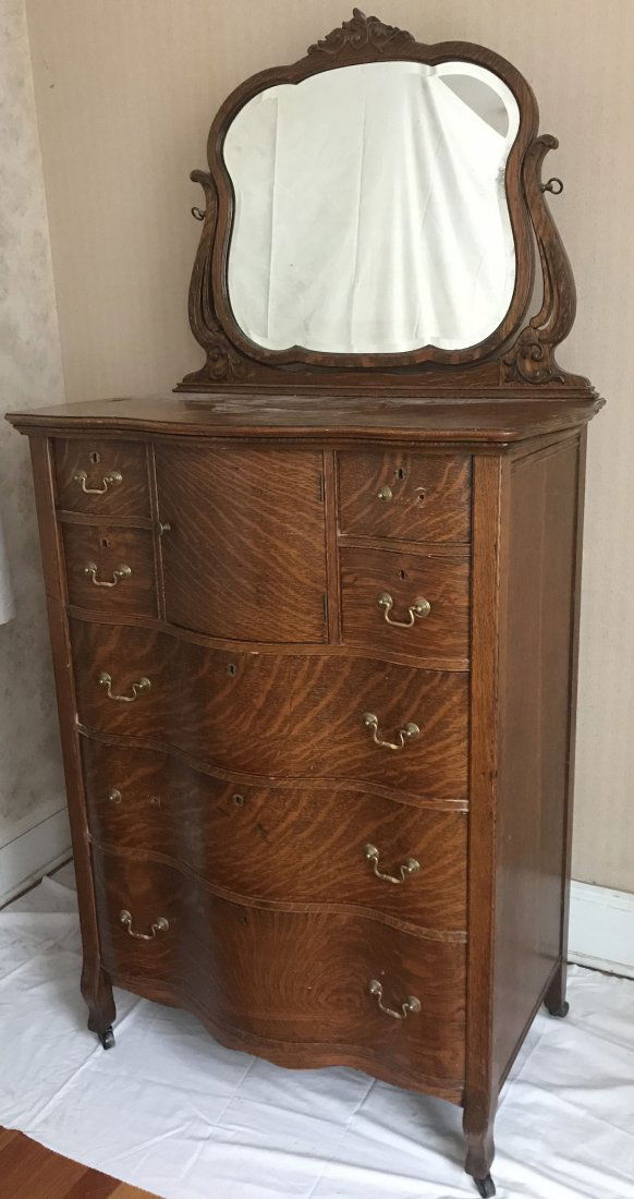 Early 20th Century Tall Chest: Early 20th century oak tall chest of drawers w/attached mirror, applied leaf carving, serpentine front w/bonnet box flanked by 4 short drawers over 3 full length drawers; some hardware off but in draw