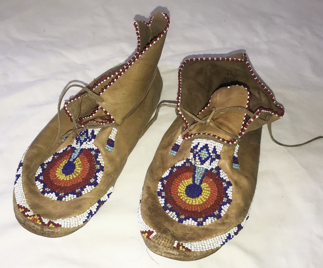 Vintage Pair of Native American Moccasins: Vintage pair of leather Native American moccasins w/bead work in red, white, blue, yellow and orange w/laces, soles show wear from use, leather uppers show some spotting and discoloration, left moccas