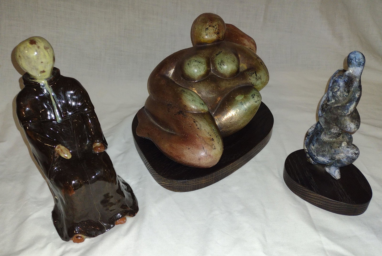 Lot o 3 Contemporary Sculptures: Lot of 3 contemporary sculptures: pottery abstract nude reclining, resting on wooden base signed Carol Way '94 Ella, 7 1/2" T x 11" W x 9" D (measurements include the stand); pottery nude couple entwi