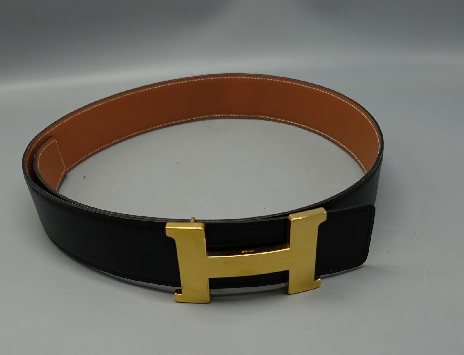 DESIGNER HERMES CONSTANCE H GOLD BUCKLE BELT BLACK LEATHER FULLY MARKED: HERMES CONSTANCE H GOLD BUCKLE BELT BLACK LEATHER--TAN INSIDE FULLY MARKED-very good condition-length 40"-three holes-can be adjusted-Provenance: From the Estate of Barbara Kanash art dealer and colle