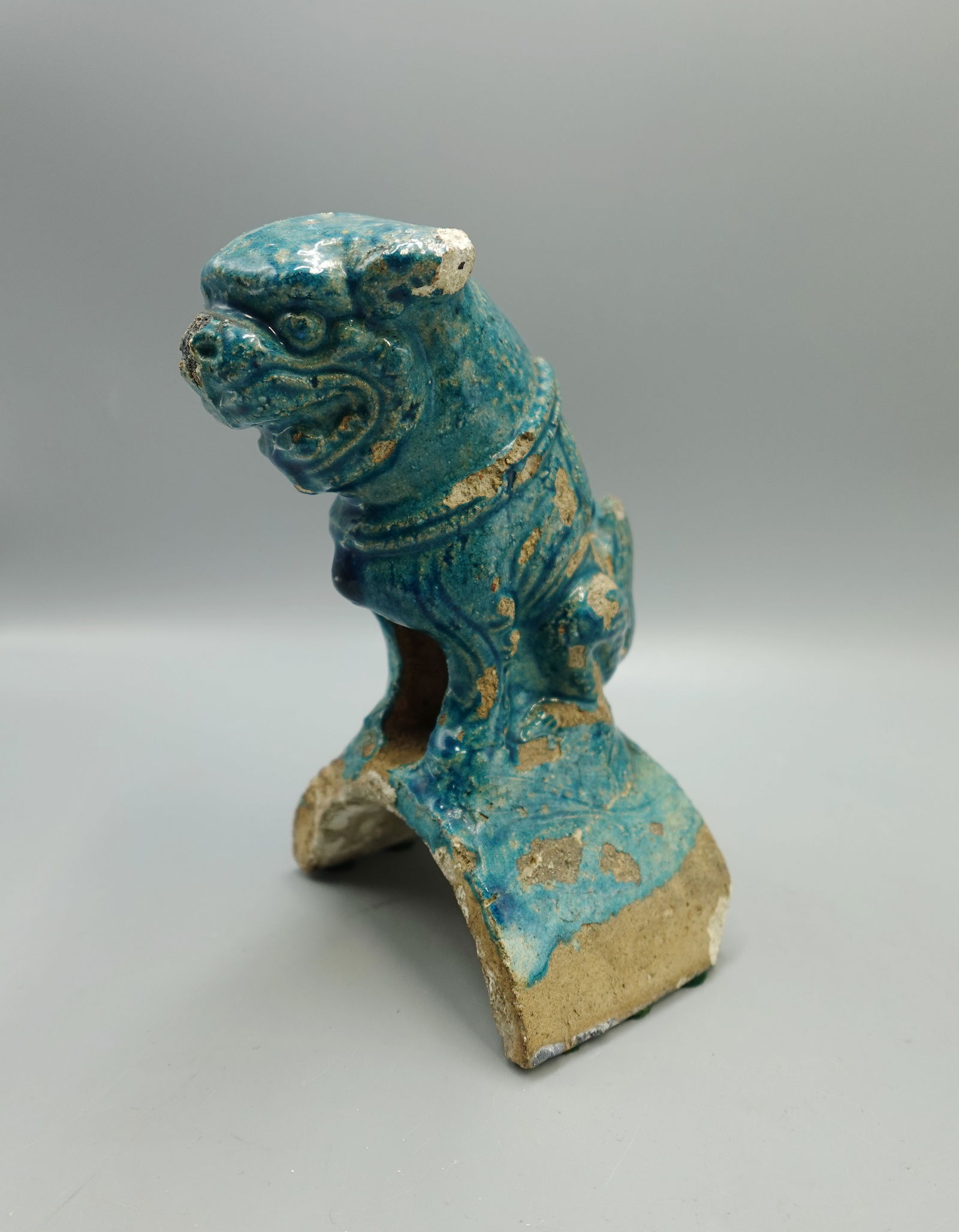 EARLY MING DYNASTY CHINESE TURQUOISE GLAZED ROOF TILE: An early roof tile example in the form of a foo dog with original turquoise glaze-Measures 7" tall and 4" wide-Has some loss to edges of ears-roughness at nose,loss to band around neck and some overal