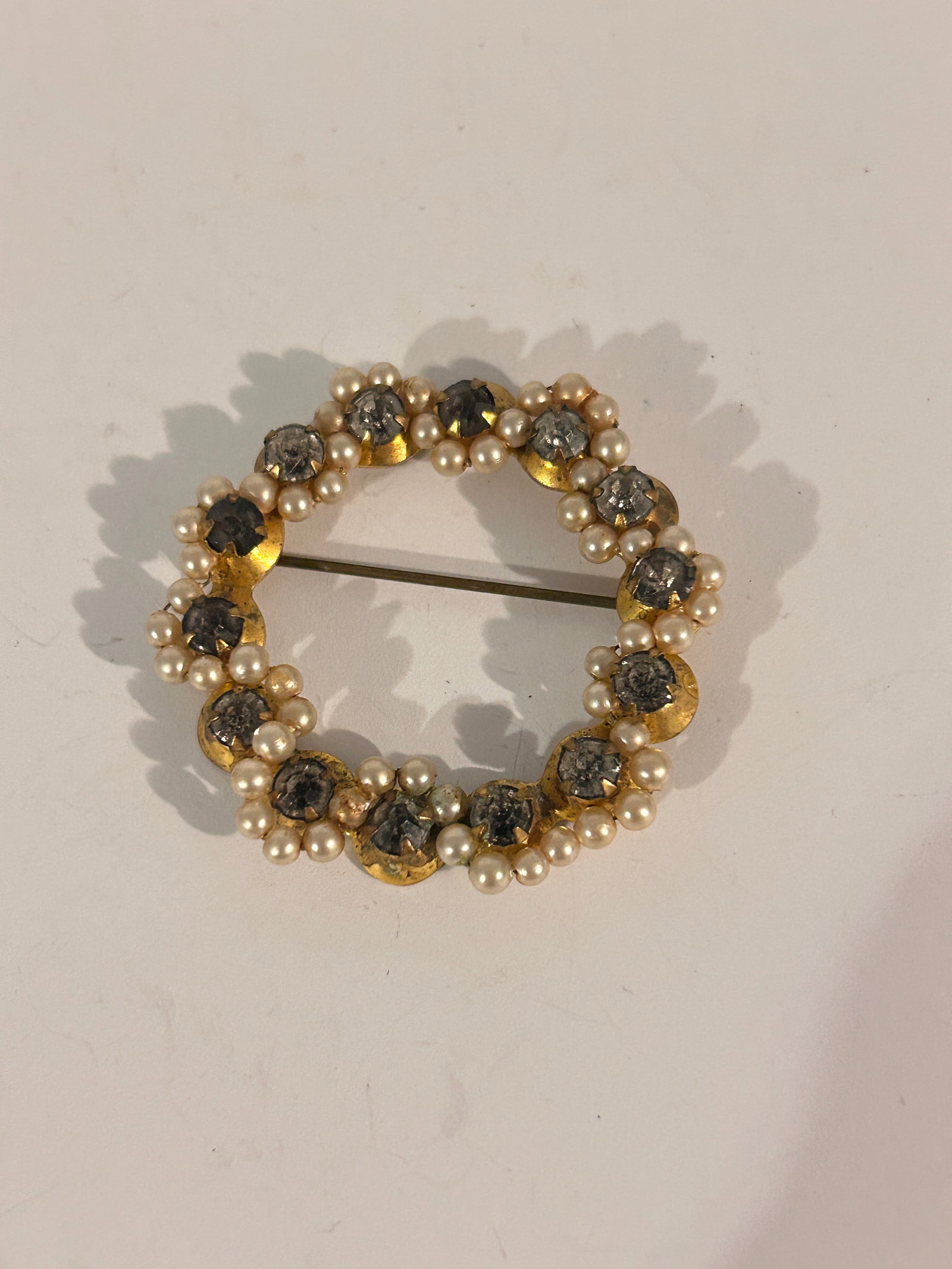 This is a vintage glass rhinestone circle wreath brooch pin with faux pearls and green-toned: This is a vintage glass rhinestone circle wreath brooch pin with faux pearls and green-toned rhinestones Please view all photos as they are part of the description and condition of this Item, Feel fre