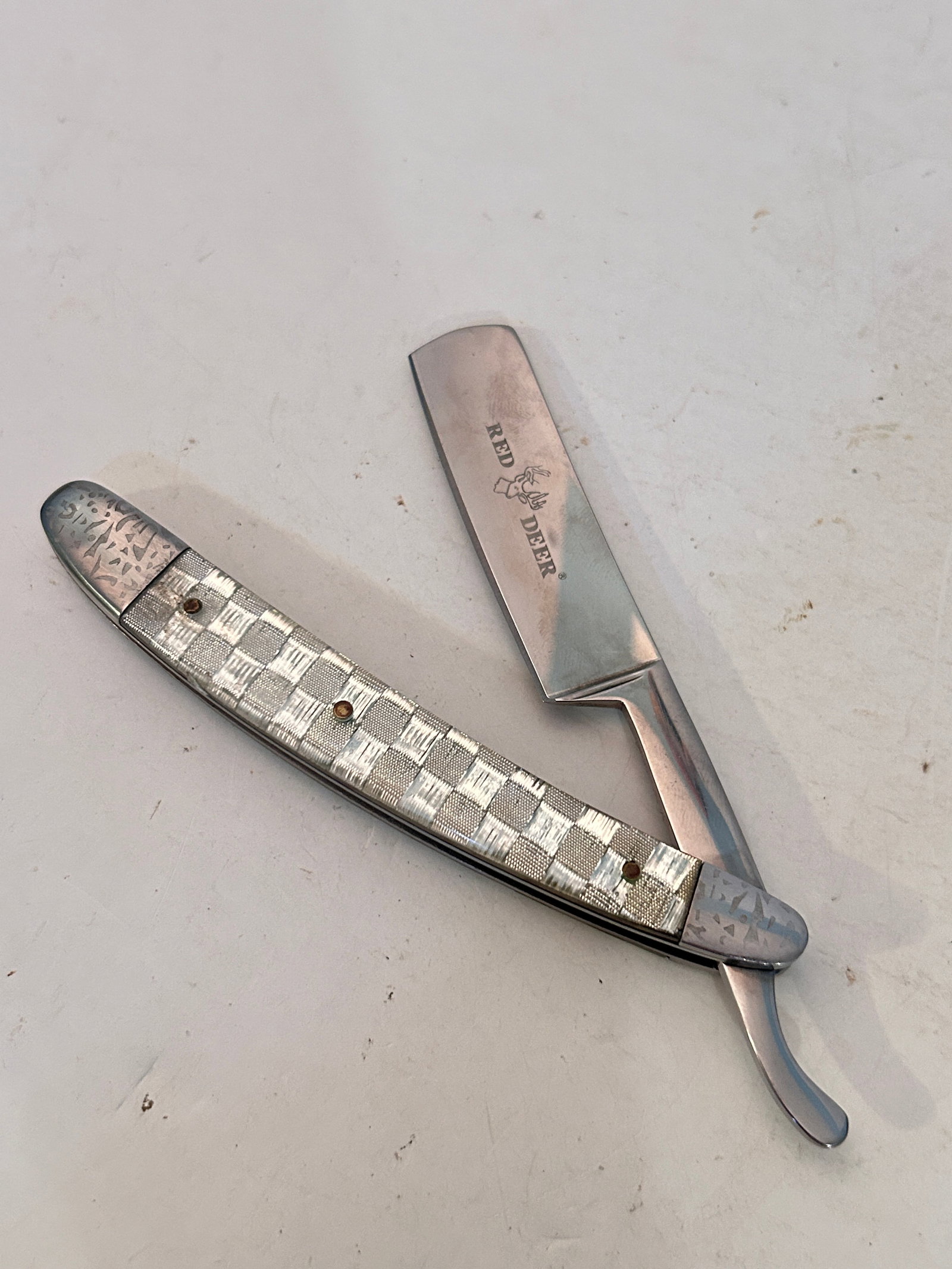 Red Deer straight razor with a distinctive silver checkerboard patterned handle.: Red Deer straight razor with a distinctive silver checkerboard patterned handle. Please view all photos as they are part of the description and condition of this Item, Feel free to contact me with que