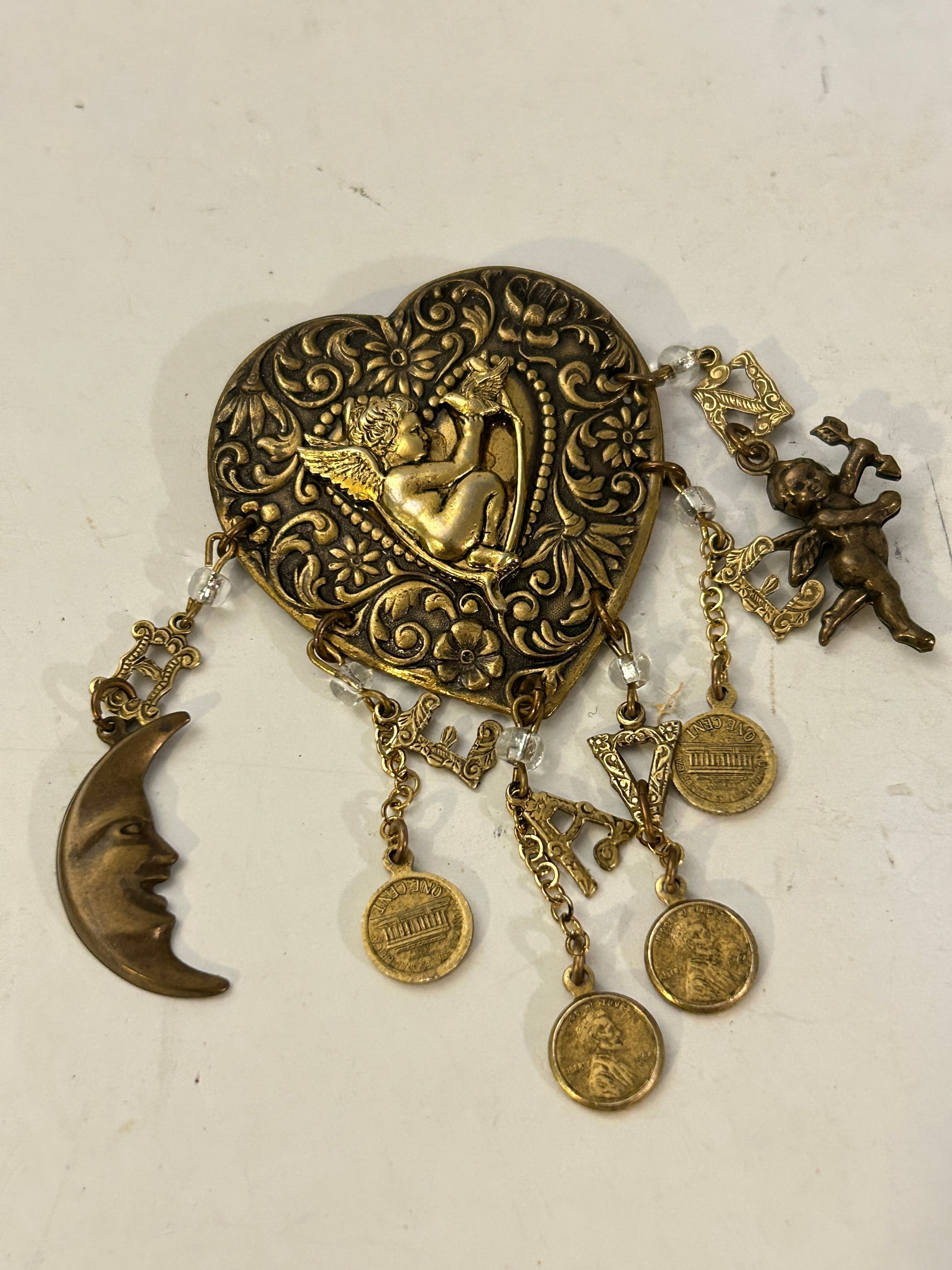 Vintage ornate brass-tone cherub and heart charm dangle Brooch: Vintage ornate brass-tone cherub and heart charm dangle Brooch Please view all photos as they are part of the description and condition of this Item, Feel free to contact me with questions or picture 