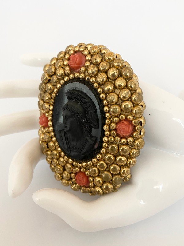VINTAGE 80'S MINADEO FAUX ORAL CAMEO ONYX GLASS BROOCH: A massive composition material brooch with carved coral rosettes and a massive hand carved genuine onyx cameo center. The piece measures 3"