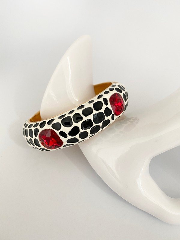 DESIGNER KENNETH LANE BLACK & WHITE ENAMEL RUBY BANGLE: A signed KJL bracelet 2 1/2" round with black and white dalmatian patterned bangle with ruby glass stones.