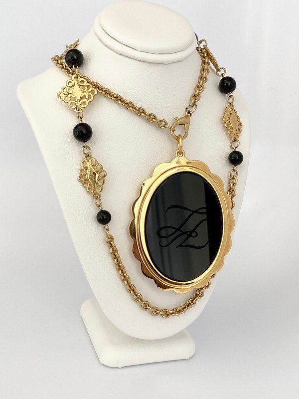 VINTAGE KARL LAGERFELD PARIS ONYX MONOGRAM NECKLACE: A vintage signed Karl Lagerfeld pendant and brooch combo on a 30" clasped removable chain. The pendant has an intaglio cut KL logo in solid onyx glass that measures over 3"