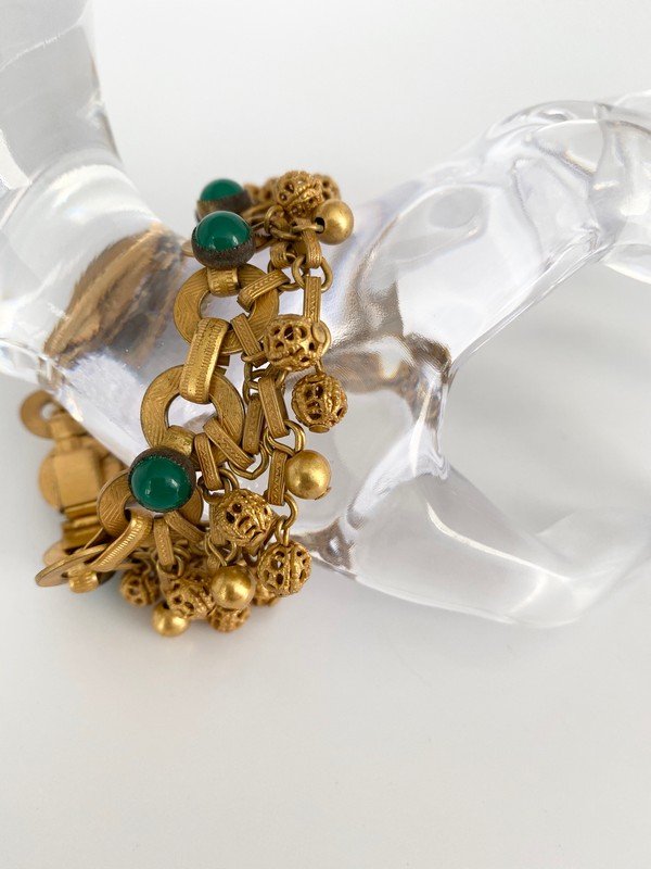 VINTAGE SIGNED HOBE BEZEL SET ETRUSCAN CHARM BRACELET: A vintage signed 7 1/2" bracelet by hobe with bezel set green glass cabochons with etruscan cha cha charm balls.