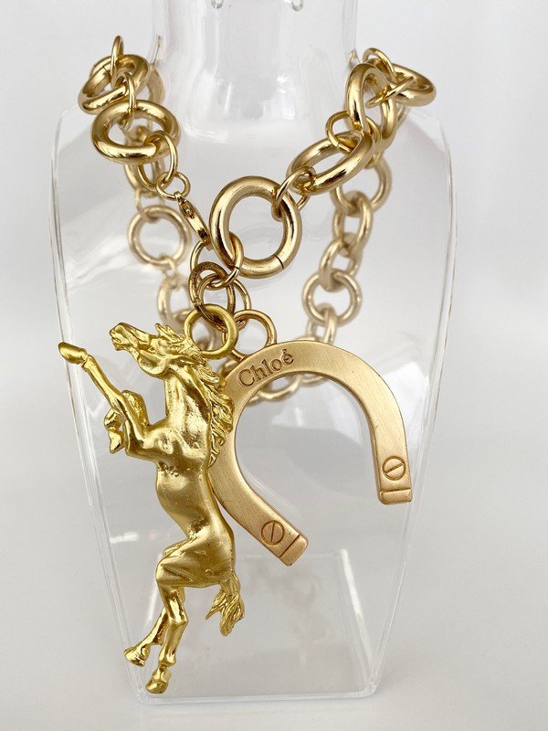 VINTAGE DESIGNER CHLOE EQUESTRIAN HORSE RUNWAY NECKLACE: An oversized necklace by Chole with a signed horse shoe with an oversized detailed horse pendant that measures 4". the necklace measures 20"