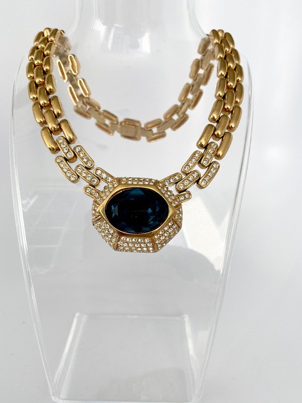 VINTAGE SIGNED CINER FAUX SAPPHIRE RUNWAY NECKLACE: A vintage never worn necklace by ciner made of heavy goldplated metal with hundreds of hand set clear crystals surrounding a massive close to 2" centerpiece with facet cut sapphire glass. Fits up to a