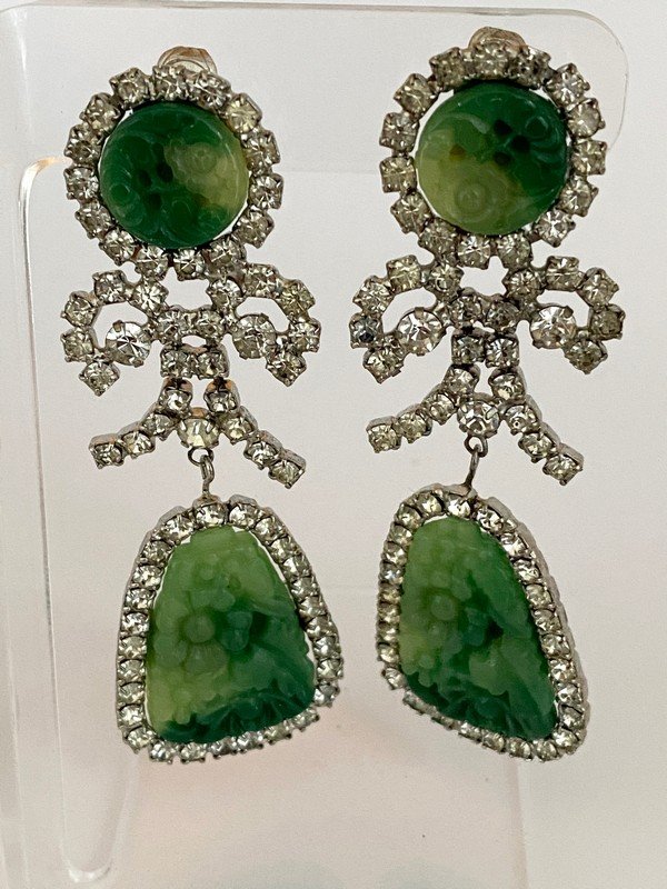 VINTAGE K.J.L. RUNWAY CARVED JADE CHANDELIER EARRINGS: An early close to 4" pair of ear clips signed K.J.L. Each of the Kenneth Lane earrings features an intricate carved jade resin panel surrounded by a prong set clear rhinestone bow formation