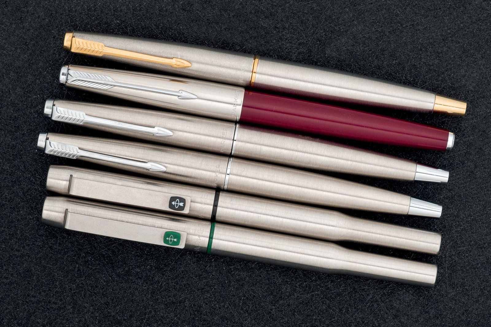 Six Parker fountainpens: Lote de seis estilográficas marca PARKER, realizadas en metal y resina roja con aros de diferentes colores.