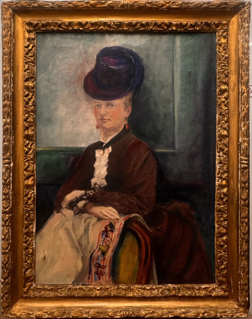 19th-Century French Oil Portrait of an Elegant Seated Lady in Ornate Gilt Frame: A refined 19th-century oil-on-canvas portrait depicting an elegantly dressed woman seated in an interior setting. The sitter wears a dark, formal gown with delicate lace cuffs, a cream skirt adorned w
