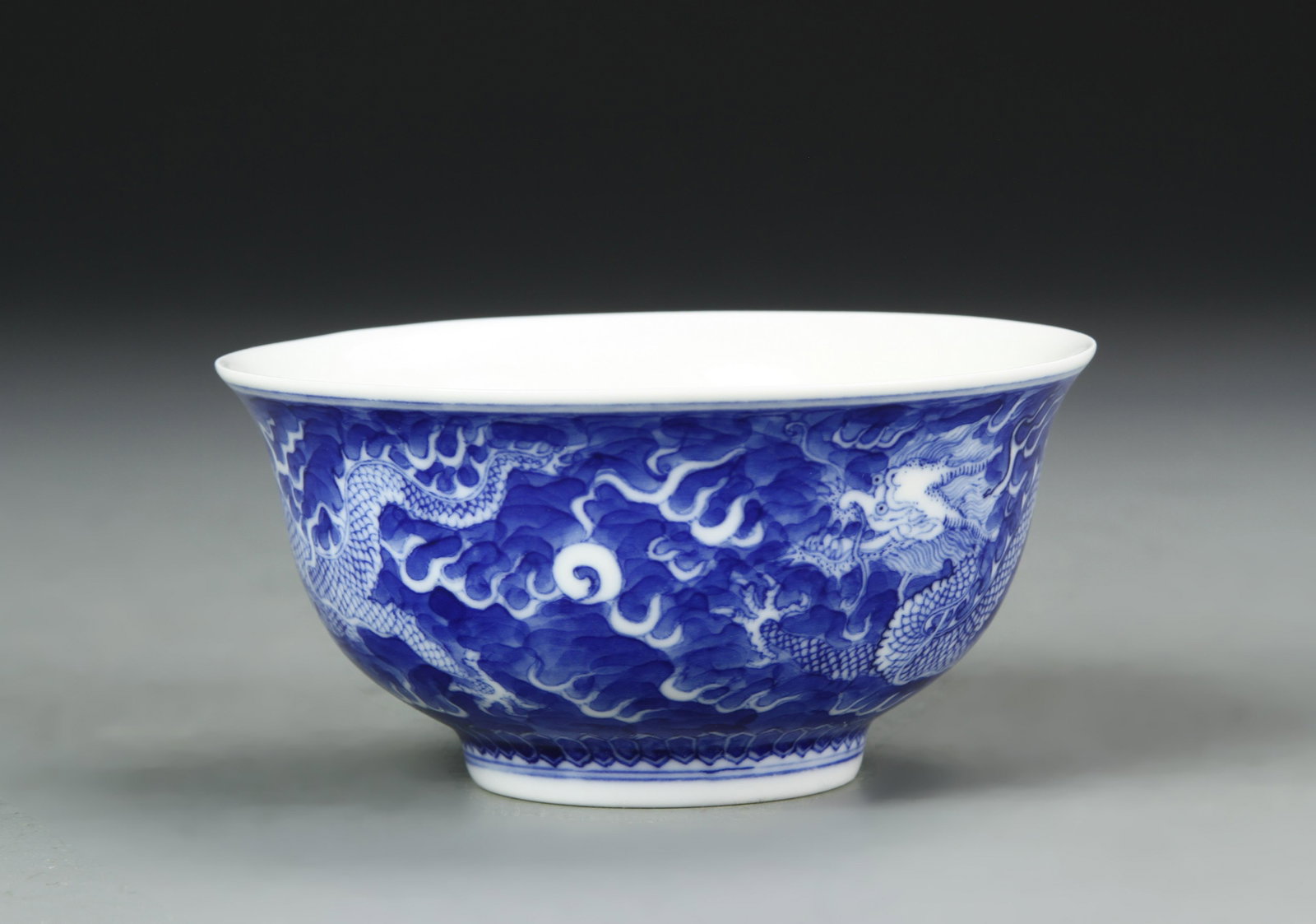 Chinese Blue and White Bowl: China, 19th C., blue and white bowl, flared rim at mouth, undulating sides to footed base, plain interior, dense blue dragon designs around exterior with Kangxi mark on base. Height 1 7/8 in., Width 3