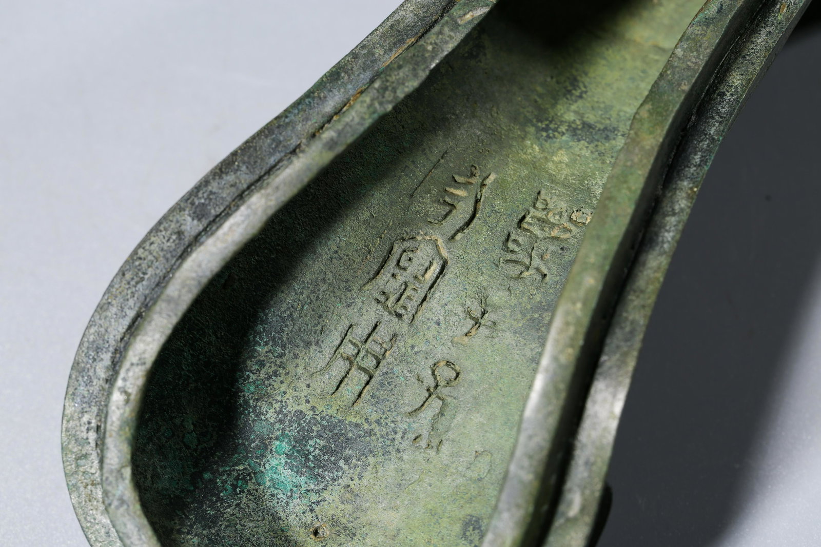 A CHINESE BRONZE WINE VESSEL, GONG: The vessel is raised on an oval pedestal foot and has a C-form handle issuing from a bovine mask at one end. The cover is cast on top with the body of carved archiastic motis that terminates in the la