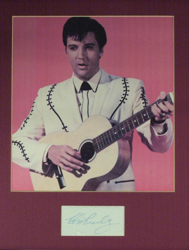 Singing Legend ELVIS PRESLEY - Signature Matted: Elvis Presley. 3 ½" x 1 ¾" (exposed) signature on a napkin matted with a 9" x 10" printed color photograph to 11" x 14".