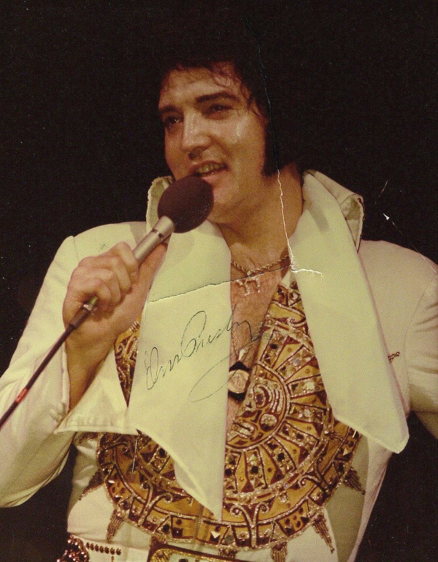 ELVIS PRESLEY - Photo Signed: Elvis Presley. 8" x 10" color photograph signed. Unfortunately there is a 3 ½" x 3" tear in the center of the photograph, not touching the signature, that has been crudely repaired with tape on the b