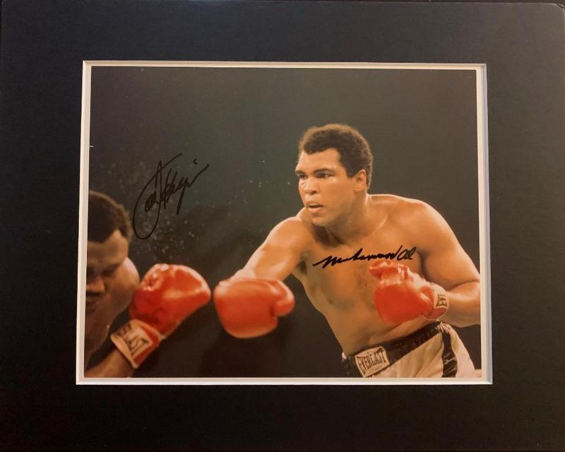 Frazier/Ali Signed Photo: Muhammad Ali (1942-2016) and Joe Frazier (1944- 2011) Heavyweight Champions. 10” x 8” color photo thought to be from their 3 rd fight signed by both fighters. The photo is matted to 14&rdq
