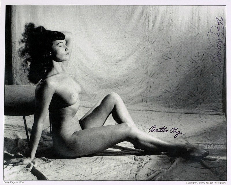 BETTIE PAGE & BUNNY YEAGER - Nude Photo Signed: Bettie Page (1923-2009) Pin-up model. Page was a struggling actress when she began posing for photographs in the late 1940s. Her shapely figure, easy smile and trademark hairstyle, long black hair wit