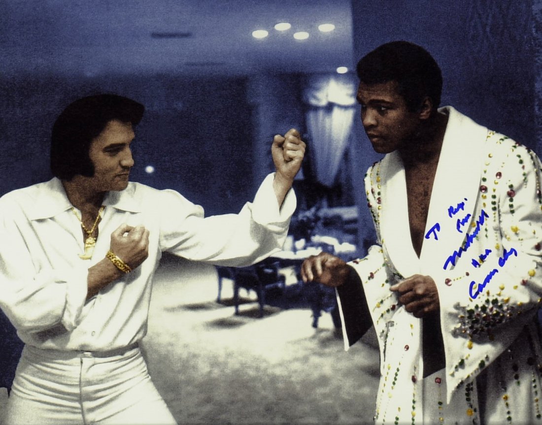 MUHAMMAD ALI - Photo With Elvis Signed: Muhammad Ali. 10” x 8” color photograph of Ali squaring off against an Elvis impersonator signed, “To Rudy, from Muhammad Ali AKA Cassius Clay.”