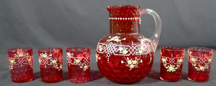 VINTAGE RUBY RED GLASS PITCHER AND FIVE GLASSES DECORATED WITH FLOWERS.