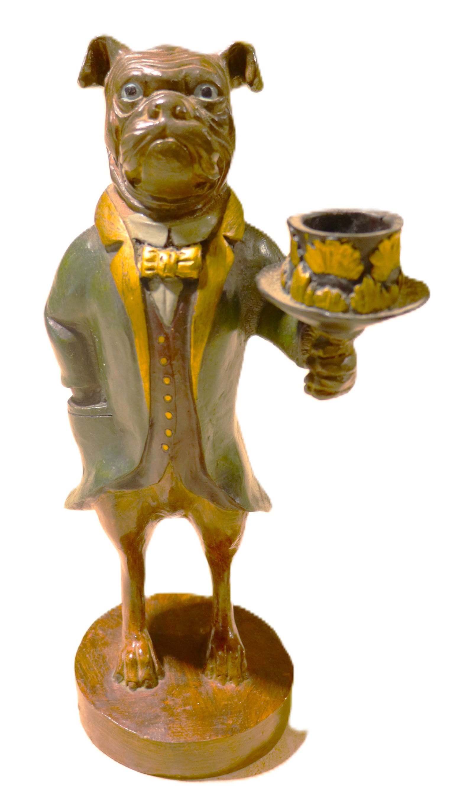Bulldog butler candle holder:  Bulldog butler candle holder The figurine depicts an anthropomorphic bulldog or boxer dog dressed in formal attire, holding a top hat that serves as a candle holder or matchstick holder. DIMENSI