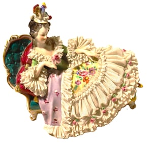 Dresden porcelain lace figurine of a lady reclining on a chaise lounge.