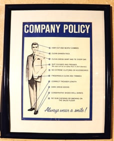 Framed  "Company Policy" sign outlining a strict dress code for sales floor employees. The policy is