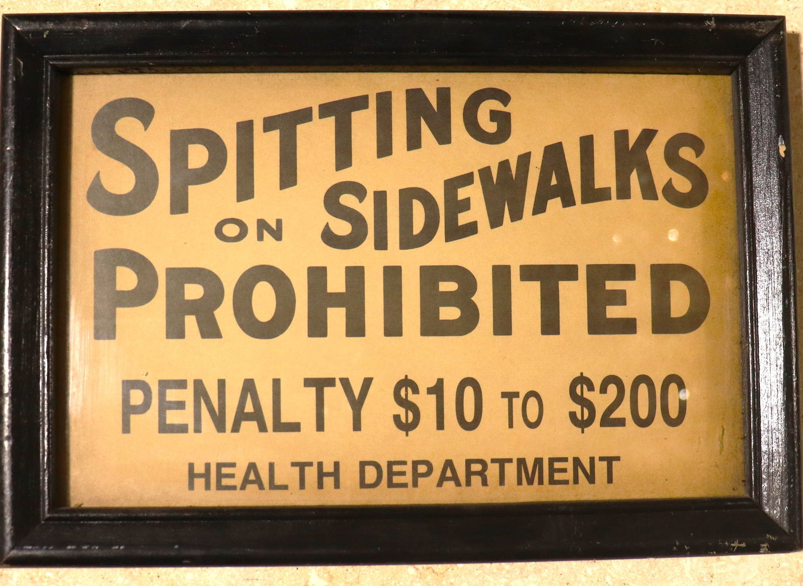 Framed Vintage sign that prohibits spitting on sidewalks.: Framed Vintage sign that prohibits spitting on sidewalks.vintage sign that prohibits spitting on sidewalks. The sign shown appears have been used by a local Health Department to enforce