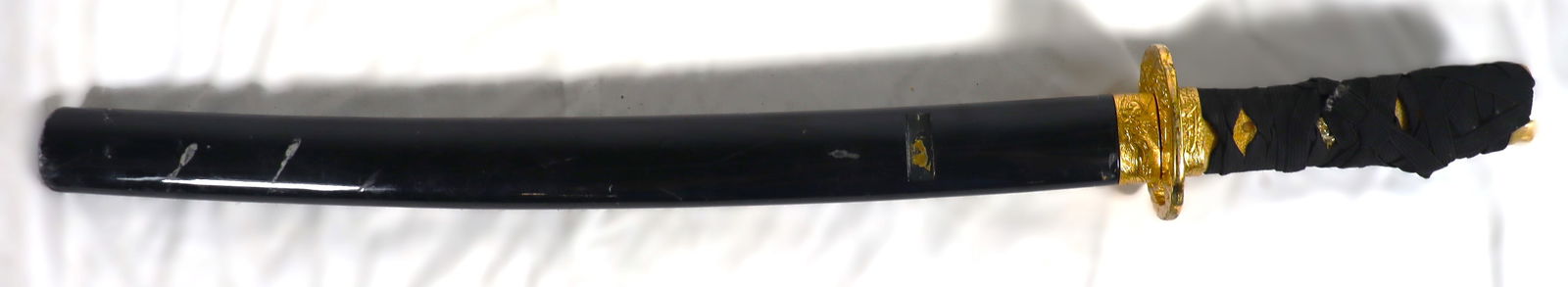 Replica of traditional Japanese samurai sword, a katana with saya (scabbard).: Replica of traditional Japanese samurai sword, a katana with saya (scabbard). This specific sword features a black scabbard and gold-colored hilt fittings, which is a common combination for both funct