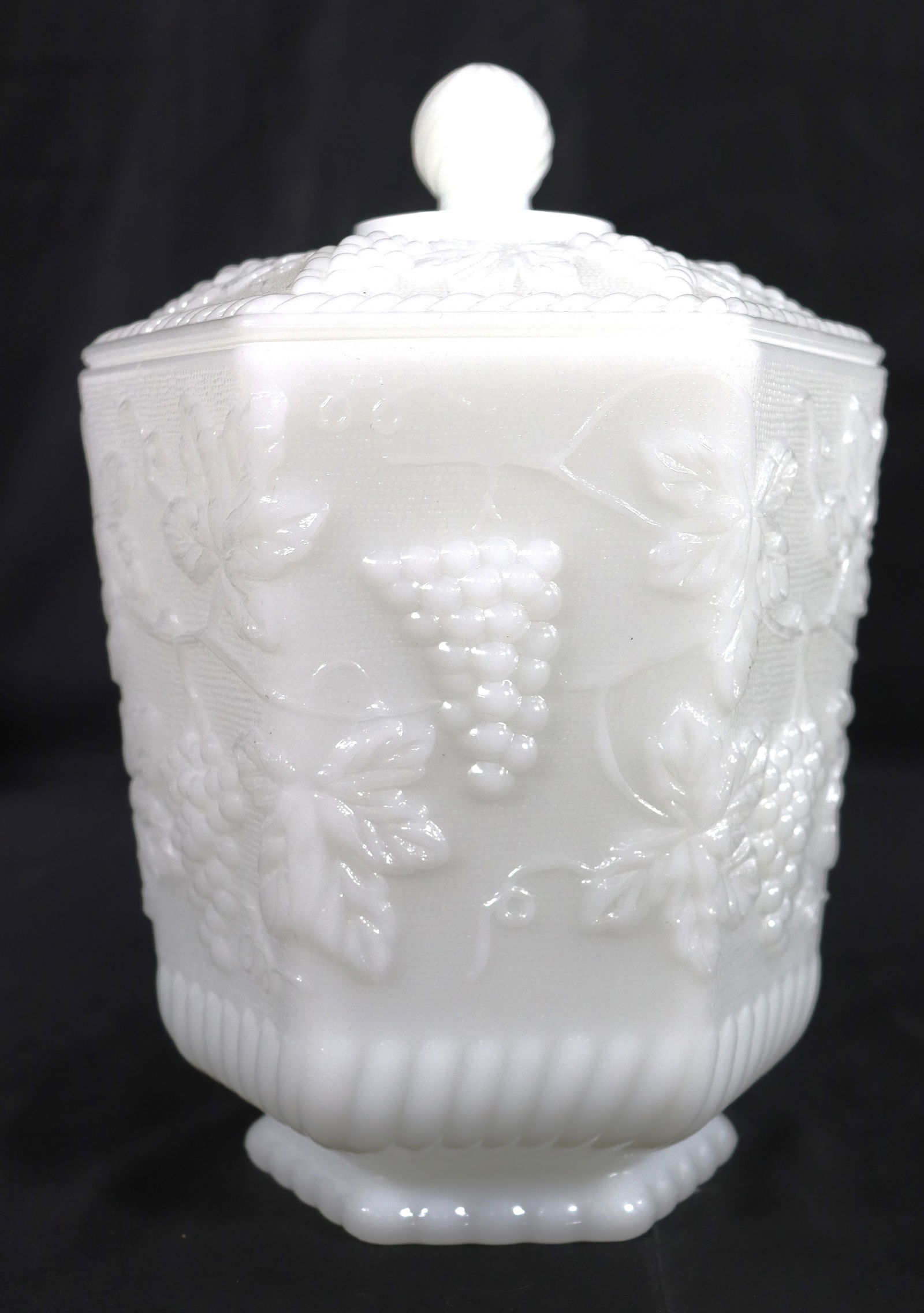 Vintage Anchor Hocking Fire-King milk glass cookie jar: Vintage Anchor Hocking Fire-King milk glass cookie jar, featuring a hexagonal shape and an embossed "Harvest Grape" or "Grape Panel" pattern. Anchor Hocking, often marked as