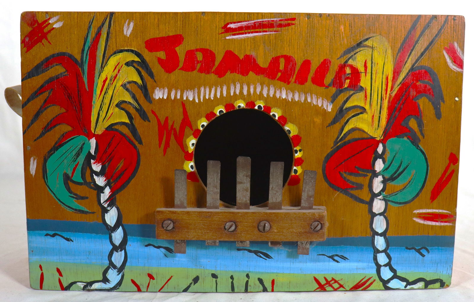 A hand-painted wooden rumba box, also known as a marimbula: A hand-painted wooden rumba box, also known as a marimbula, which is a traditional Jamaican musical instrument, It is a large lamellophone (finger harp) with metal tines that are plucked to