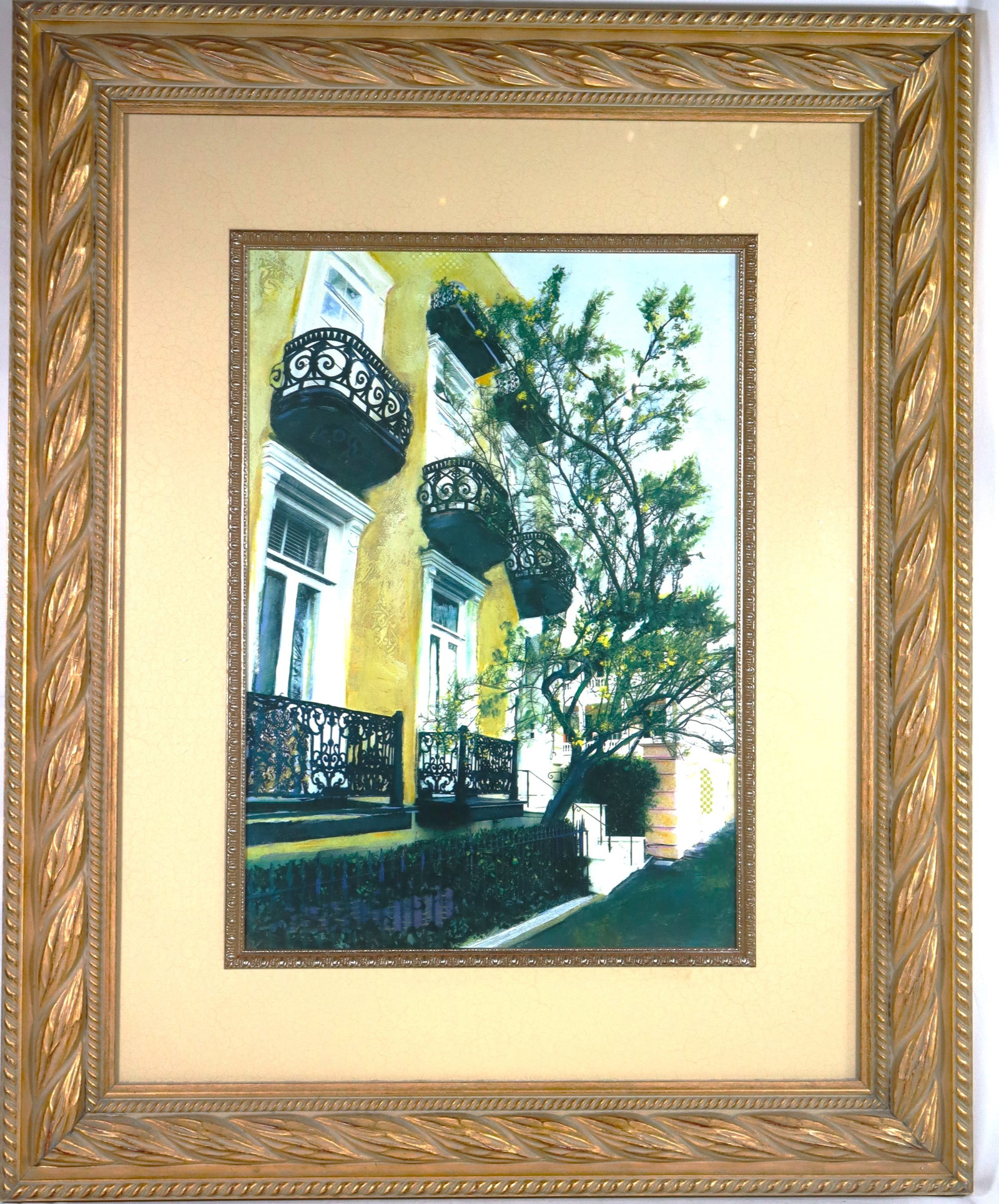 Framed mixed media artwork unsigned titled "Courtyard": Framed mixed media artwork unsigned titled "Courtyard" The artwork depicts a yellow building with distinct black iron lace balconies and a tree in the foreground The style is evocative