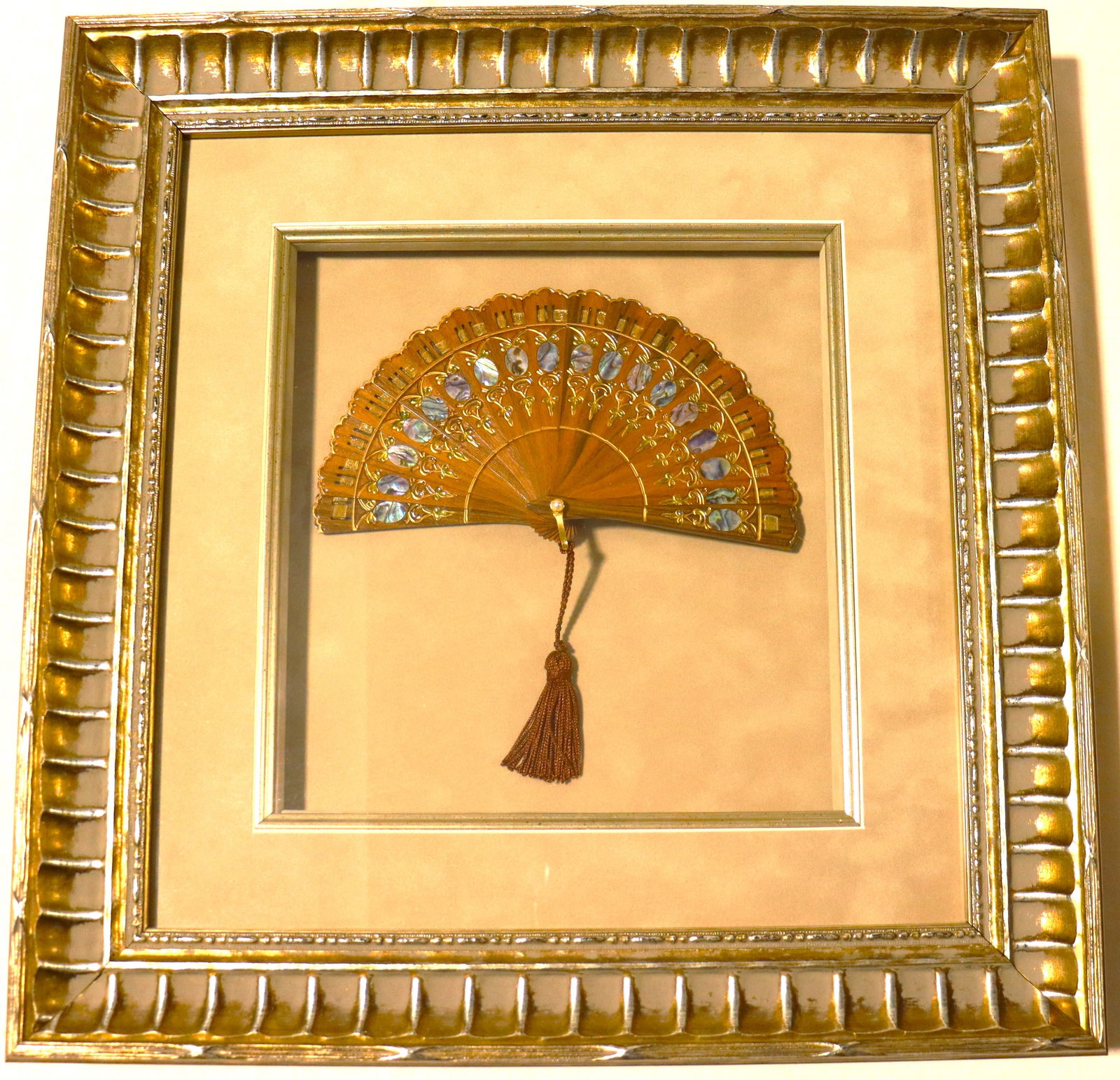 Framed vintage wooden folding hand fan featuring intricate mother-of-pearl inlays: Framed vintage wooden folding hand fan featuring intricate mother-of-pearl inlays, gold-toned filigree, and a decorative tassel. DIMENSIONS with frame: Height 17.50 inch / 44,5 cm &