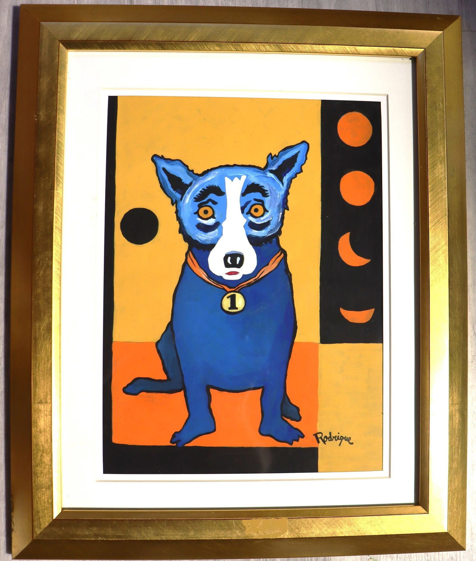 George Rodrigue Blue Dog "Number 1", Framed: This vibrant George Rodrigue's iconic Blue Dog, depicted seated with a medal bearing the number "1" around its neck. The background is a dynamic composition of yellow, orange, and black geometric shap