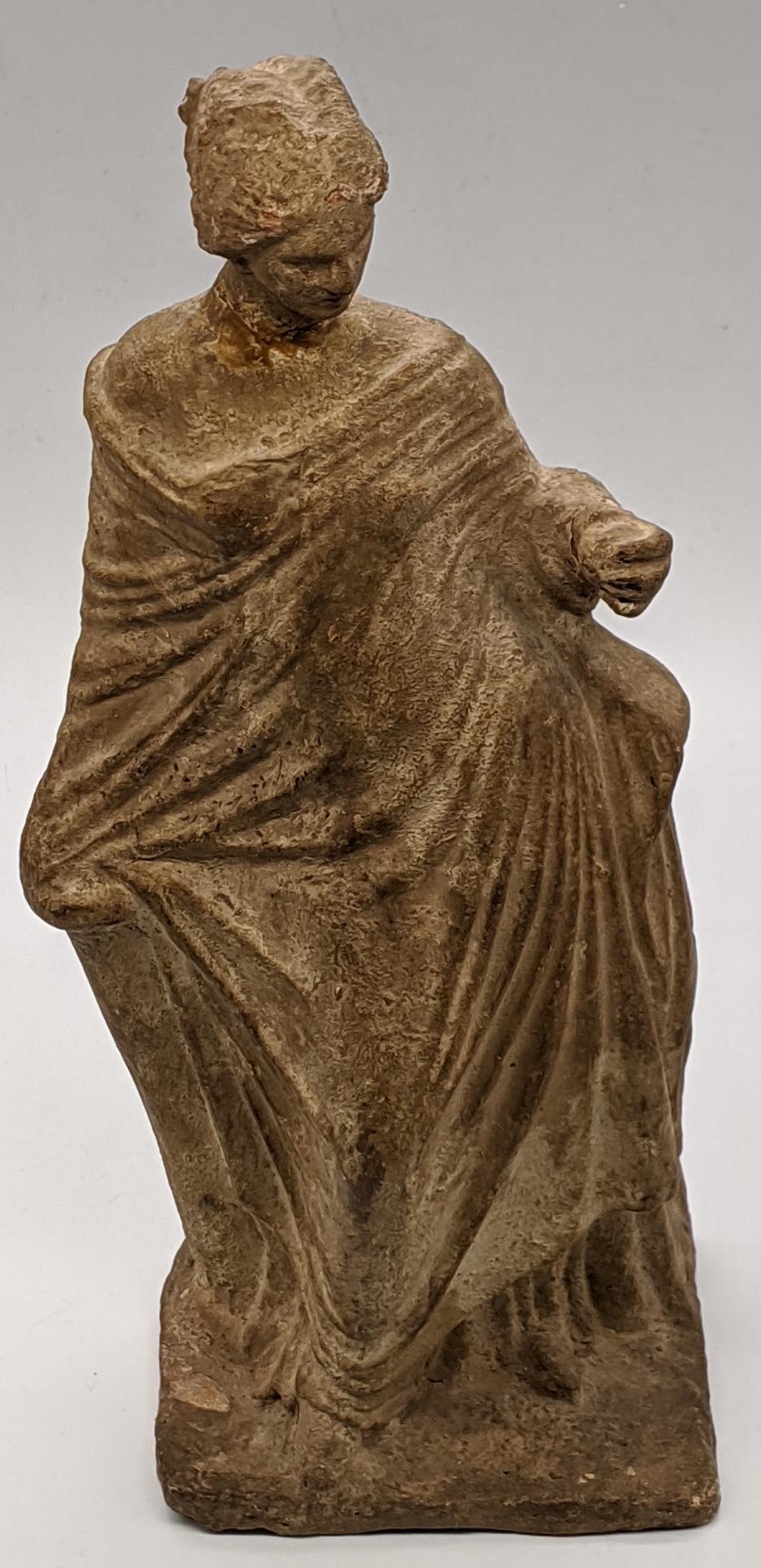 A Greek Tanagra terracotta statuette representing Venus: A Greek Tanagra terracotta statuette representing Venus and the golden apple, 19th century reproduction of the late 4th century BC original (After The Antique) H.17cm