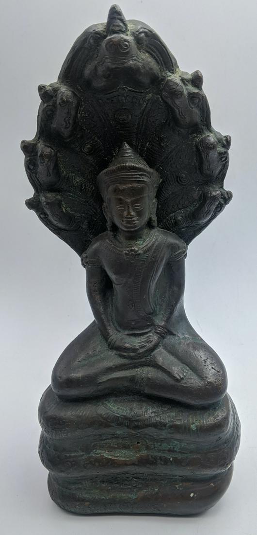 A Cambodian bronze figure of a seated Buddha in: A Cambodian bronze figure of a seated Buddha in meditation, sheltered by the hood of a seven-headed serpent, H.22cm