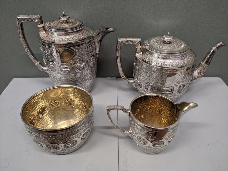 A four piece silver tea set with etched and embossed: A four piece silver tea set with etched and embossed decoration, gilt interior