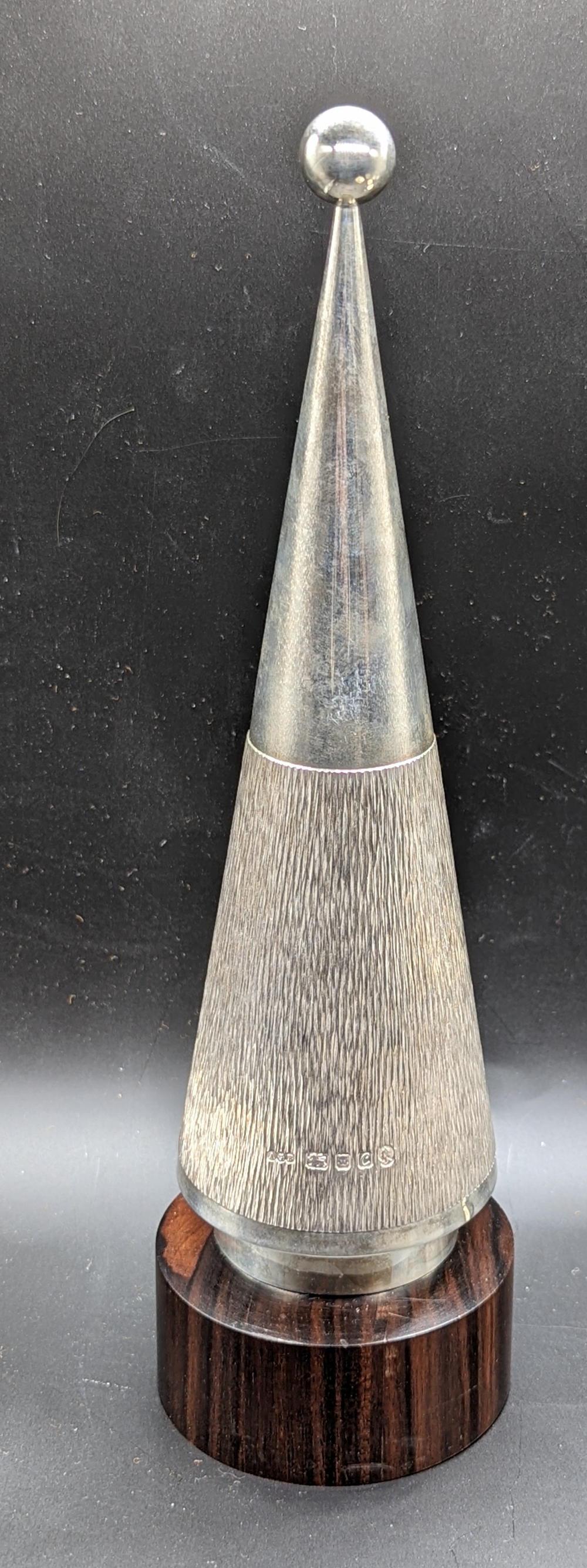 A Gerald Benney silver tennis trophy, cone shaped with tennis racquet emblem, bark effect finish,: A Gerald Benney silver tennis trophy, cone shaped with tennis racquet emblem, bark effect finish, raised on wooden base, hallmarked London, 1977, 362g, H.25.5cm