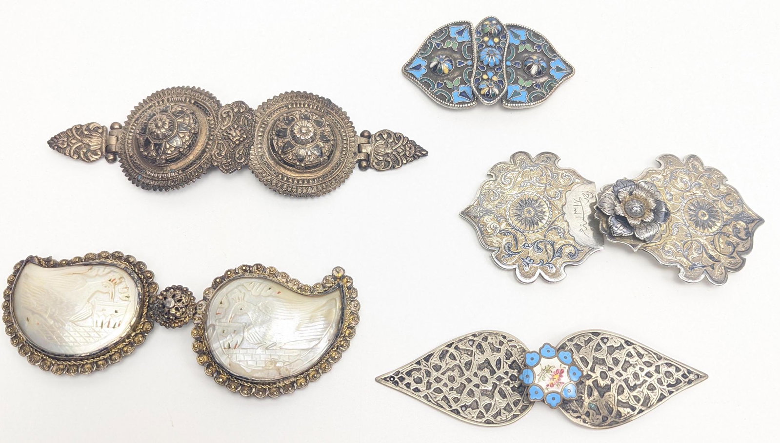 A fine collection of five Ottoman belt buckles to include a niello inlaid silver gilt buckle signed: A fine collection of five Ottoman belt buckles to include a niello inlaid silver gilt buckle signed (Ahmad) and dated 1317/1899AD, another enamelled metal one possibly Armenian Ottoman, a mother of pe